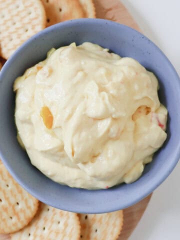 Overhead view of corn relish dip in a blue bowl surrounded by crackers.