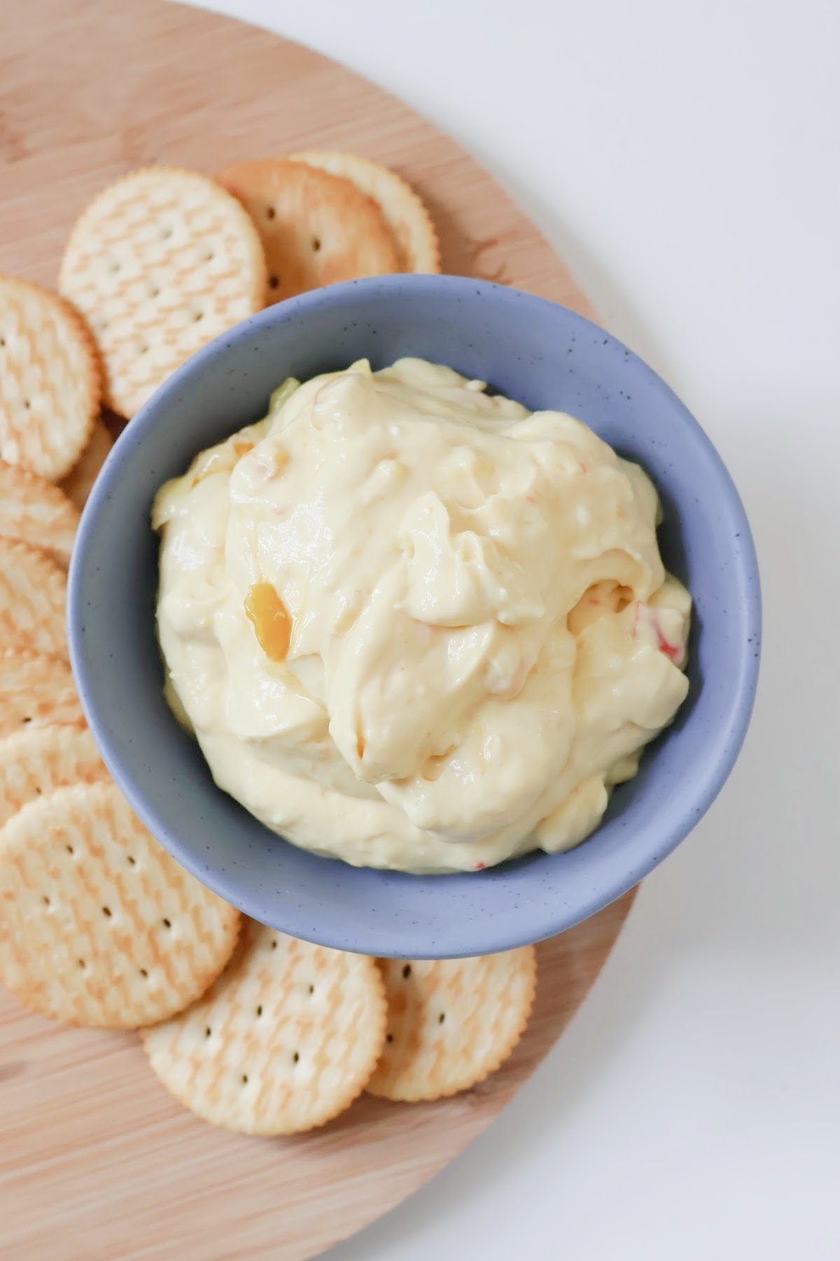 Overhead view of corn relish dip in a blue bowl surrounded by crackers.