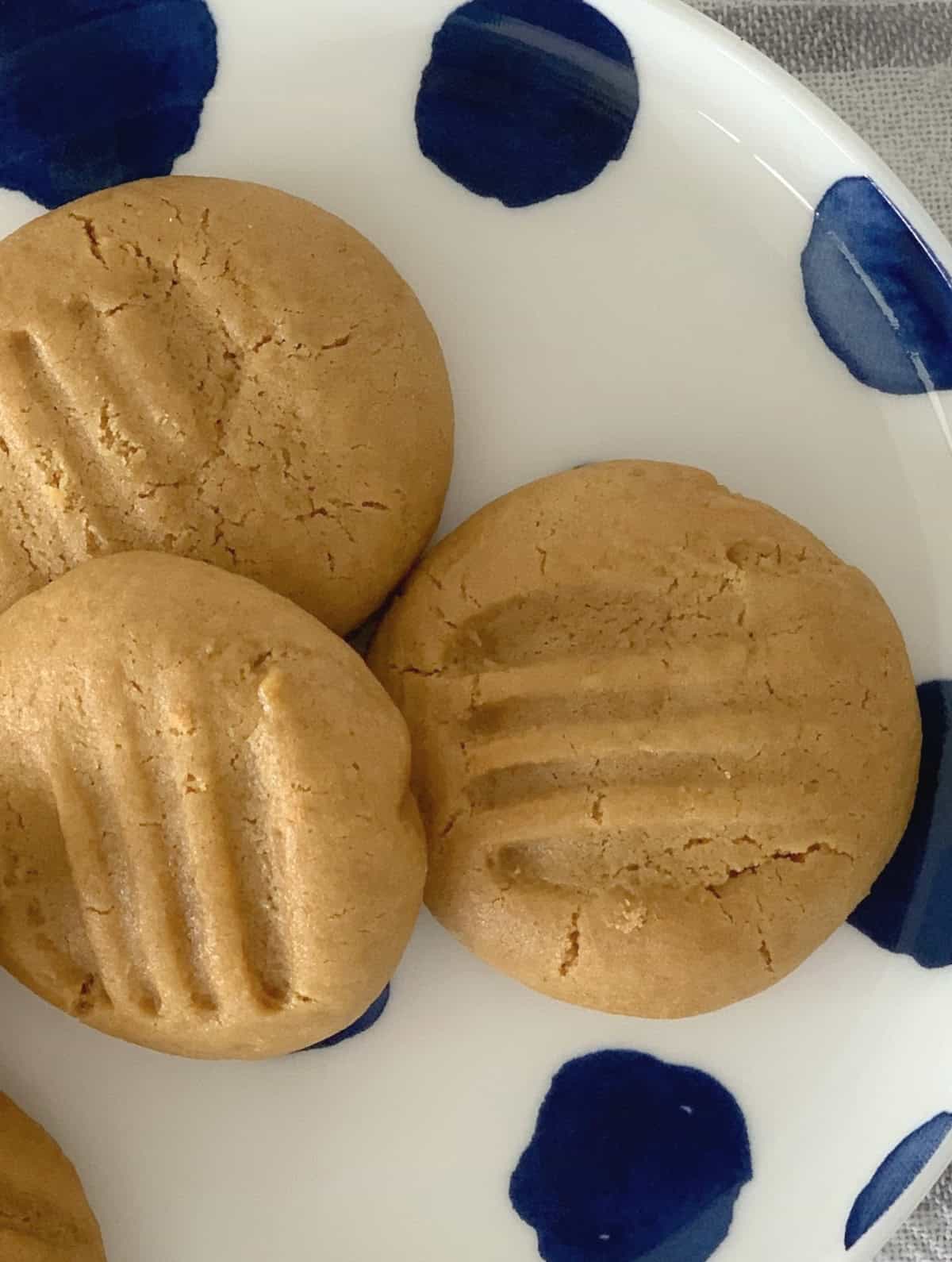 Three caramel biscuits on a blue and white spotted plate.