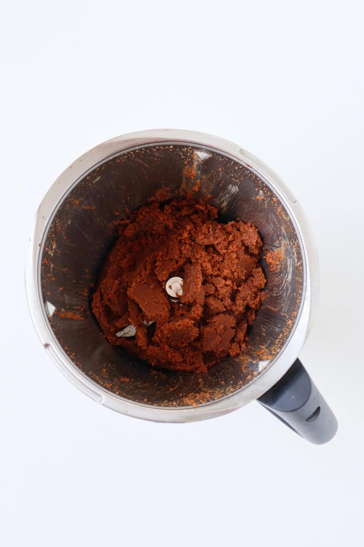 Crushed Biscoff biscuits combined with melted butter in a thermomix bowl.