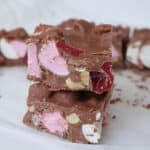 Two pieces of chocolate rocky road on top of each other. In the background is more pieces of rocky road.