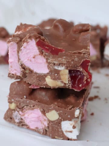 Two pieces of chocolate rocky road on top of each other. In the background is more pieces of rocky road.