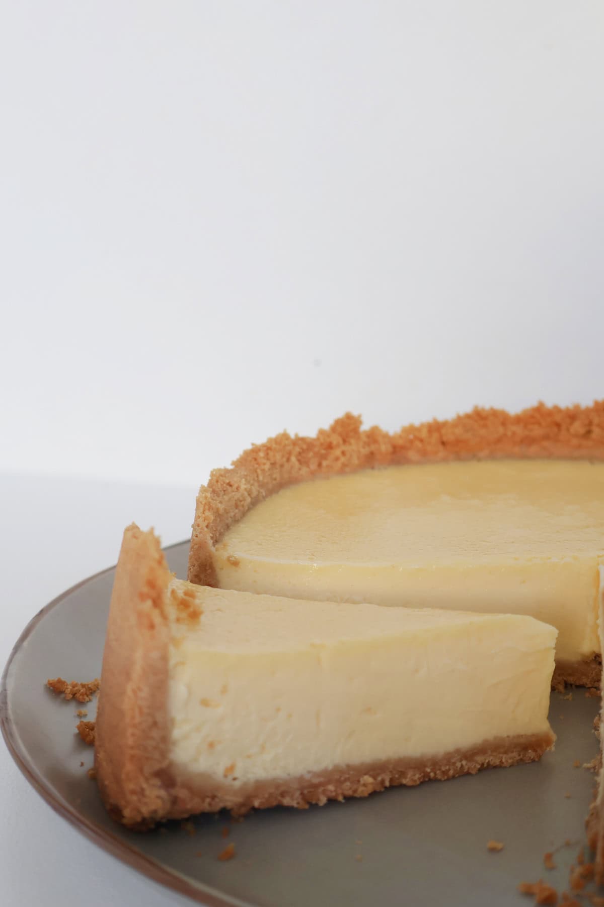 side view of baked lemon cheesecake on a plate.